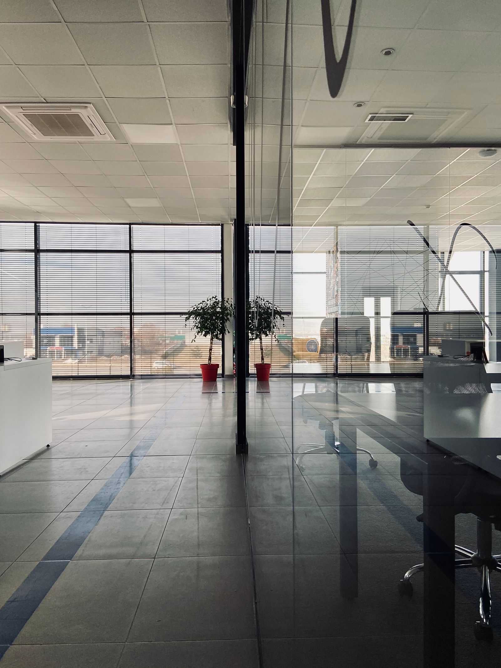 Grand espace de bureaux lumineux avec cloisons vitrées et sol réfléchissant